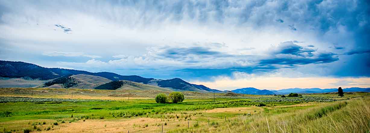 open terrain in Wyoming with mountains in the background and dramatic cloud formations 